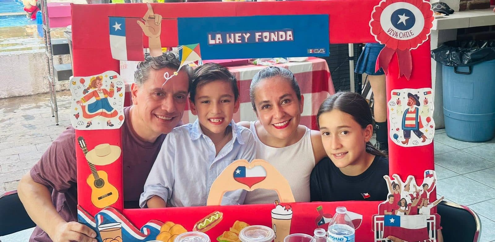 Una familia de cuatro en el marco, con la piscina y las mesas del patio detrás.