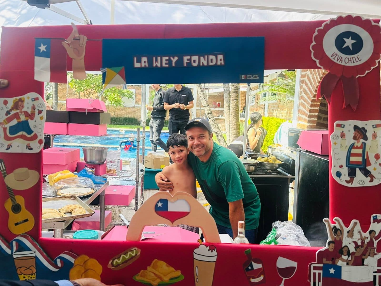 Un papá y su hijo junto al puesto de empanadas montado al borde de la piscina.